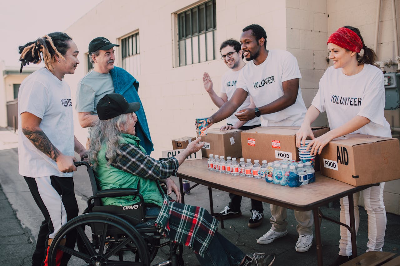 Services Volunteers distribute bottled water and supplies to diverse individuals in an outdoor setting, showcasing community support.