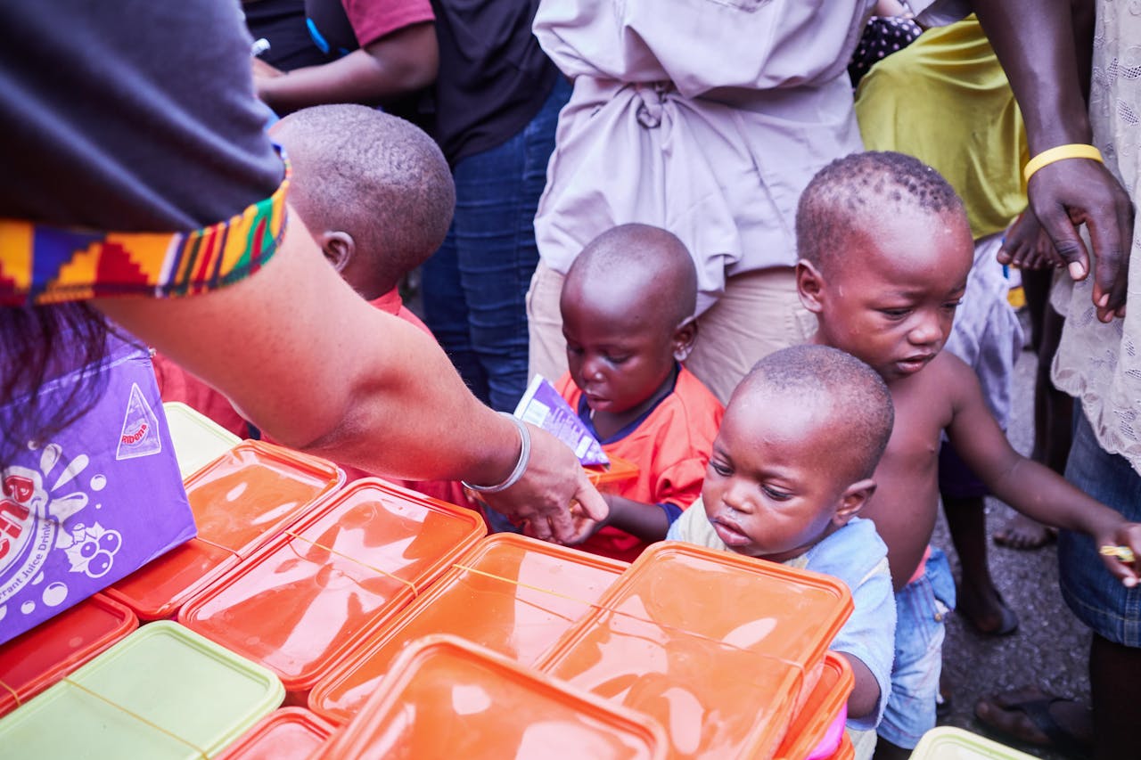 Services Young children receiving essential supplies from volunteers during a distribution event.